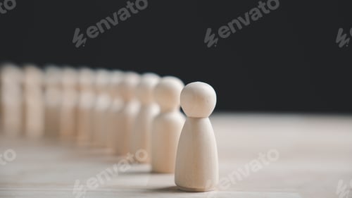 Preview: A single wooden figure stands out from a row of identical figures on a wooden table.