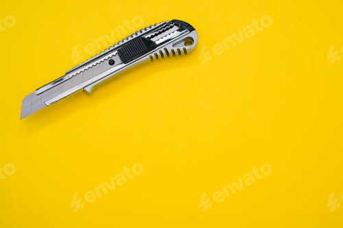 Preview: Closeup shot of a cutter blade tool isolated on yellow background. Cutting knife for cardboard