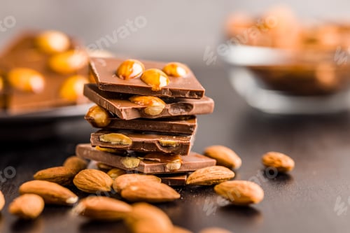 Preview: Broken chocolate bar with almonds on black table.