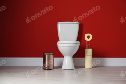 Preview: Toilet bowl with paper rolls and trash bin in restroom