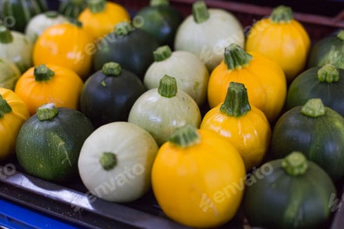Preview: Yellow green and white pumpkins are laid in a row on the counter in the rural market. Natural Bio