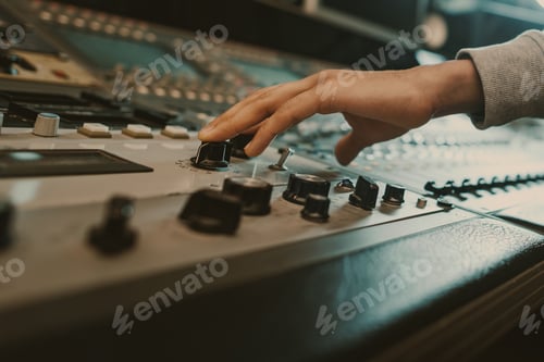 Preview: cropped shot of sound producer touching knobs on recording equipment