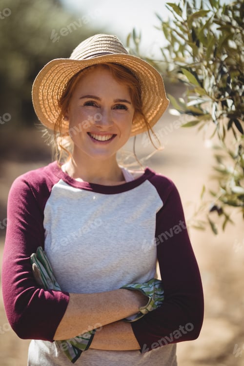 Visualização: Smiling young woman with arms crossed standing at olive farm