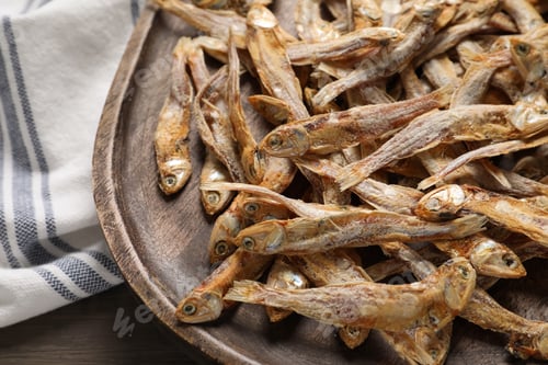 Preview: Wooden plate of tasty dried anchovies on table, closeup