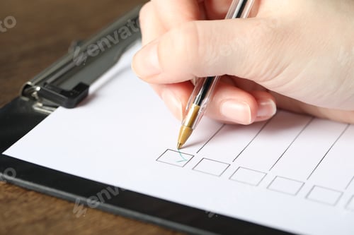 Preview: Woman checking box of paper form at table, closeup