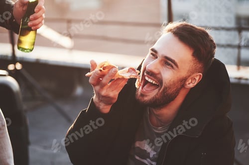 Preview: Guy eating a delicious pizza on the rooftop while having party with friends