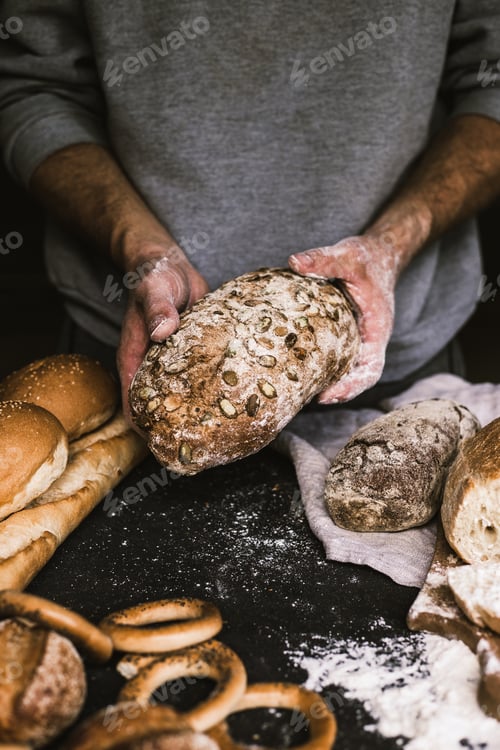 Preview: Baker man holding a rustic organic loaf of bread in his hands