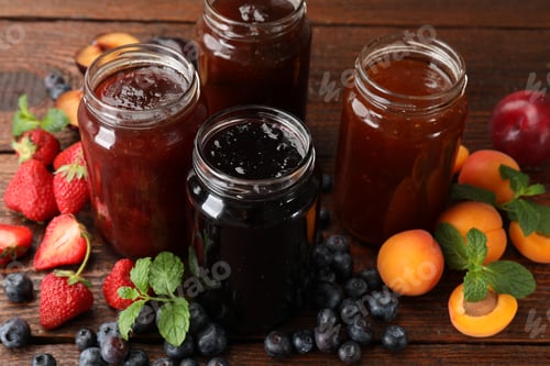 Preview: Different jams in jars and ingredients on wooden table, closeup