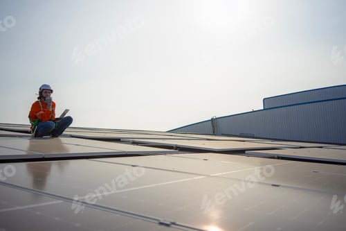 Preview: Blue collar worker is inspecting solar panel at rooftop of factory.