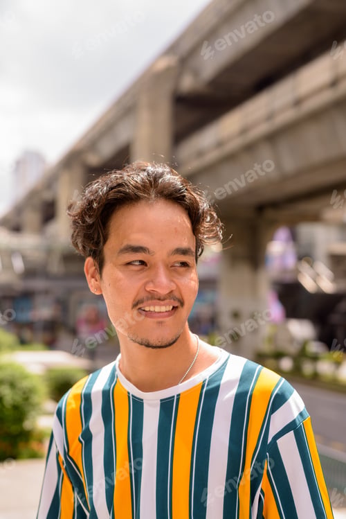 Preview: Portrait of handsome multi-ethnic young man wearing colorful shirt outdoors during summer in city