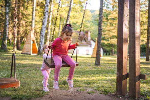 Preview: Cute little girl is rocking her older sister on the playground