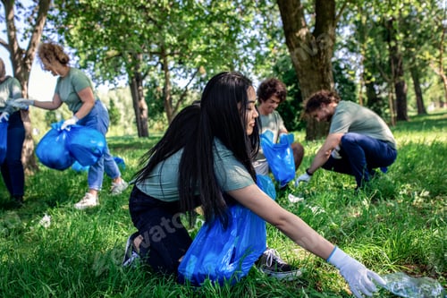 Preview: Portrait of young woman with garbage bags cleaning city park with friends.