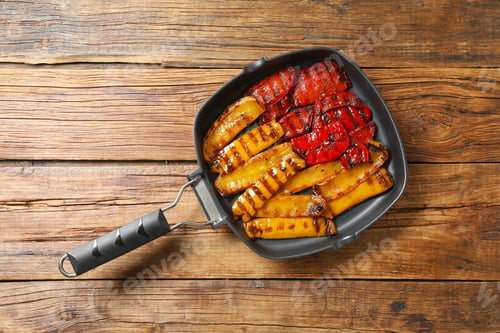 Preview: Delicious grilled peppers in pan on wooden table, top view