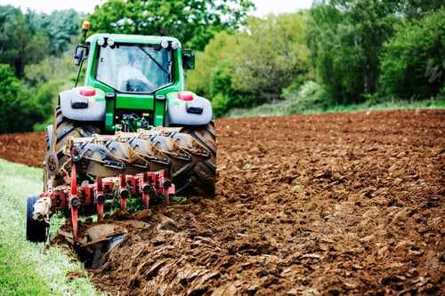 Preview: A tractor ploughing the soil in a field, harrowing.