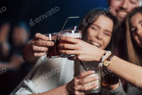 Preview: Group of young friends smiling and making a toast in the nightclub