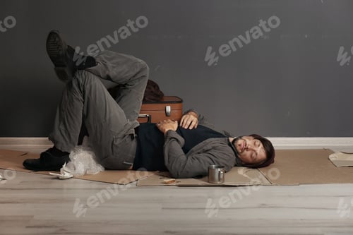Preview: Poor homeless man sleeping on floor near dark wall