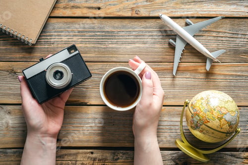 Preview: Travel composition with a retro camera and a cup of coffee in female hands.