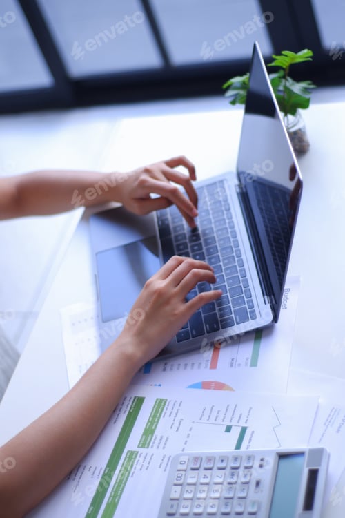 Preview: Closeup young women remote work from home analyzing data, using calculator and laptop.