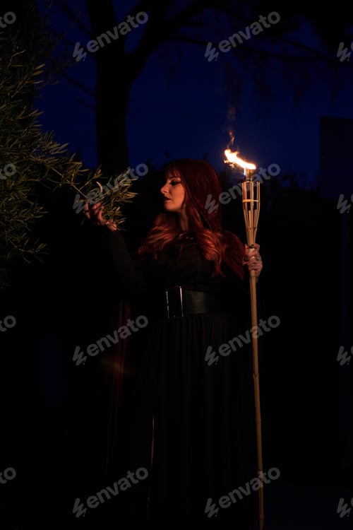 Preview: Woman disguised as a witch holding a flaming torch