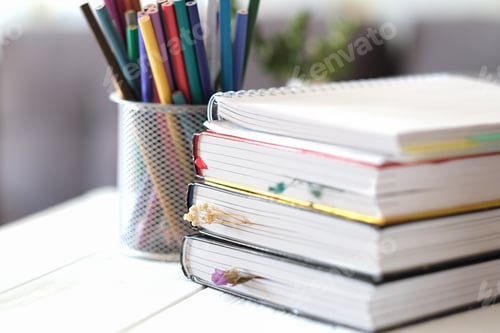 Preview: hardcovered books with dry flower bookmarks on a table. color pencils