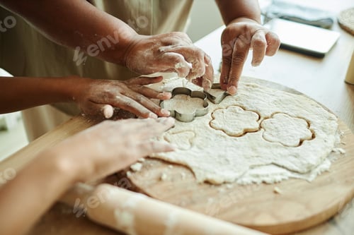 Preview: Hands of Grandma and Granddaughter Cutting Cookies from Dough at Kitchen