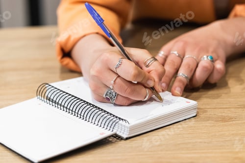 Preview: Crop woman taking notes in notebook during work in cafe