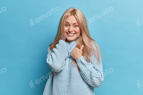 Preview: Glad blonde European female model looks gently at camera feels satisfied smiles toothily enjoys wear