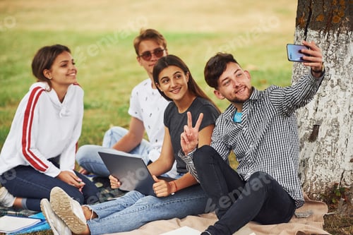Preview: Group of young students in casual clothes on green grass at daytime