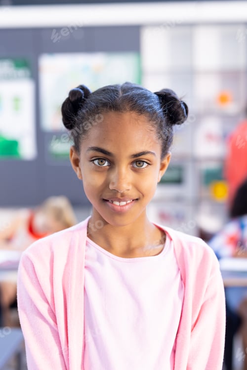 Preview: Portrait of smiling biracial schoolgirl standing in classroom with copy space