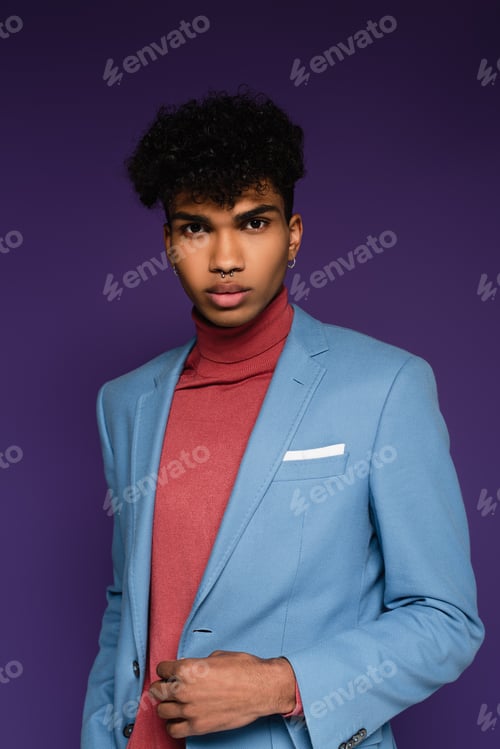 Preview: curly african american man in blue blazer looking at camera on purple