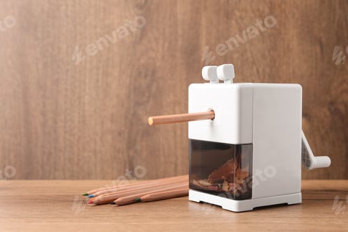 Preview: Mechanical sharpener near colorful pencils on wooden table. Space for text