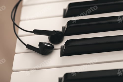 Preview: Closeup of earphones over piano or synthesizer keyboard