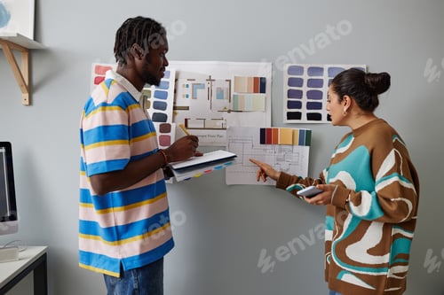 Preview: Designers of interior discussing project on the wall together while standing in office
