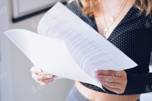 Preview: Young woman is looking at a typed document she is holding in her hands