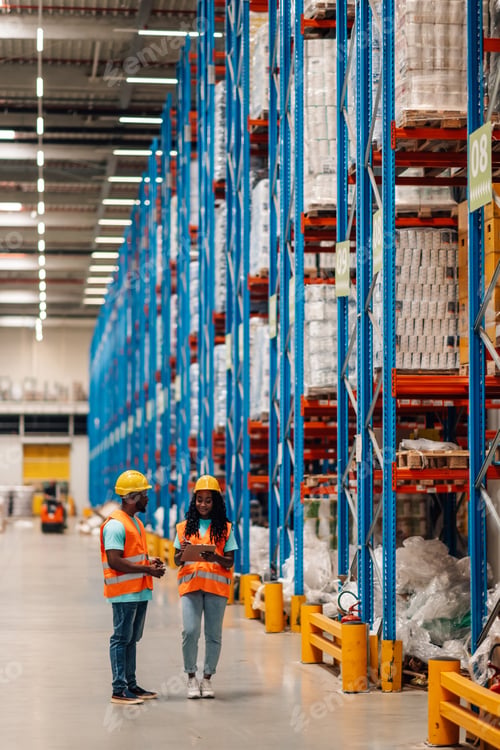 Preview: Warehouse workers discussing logistics using digital tablet in large distribution center