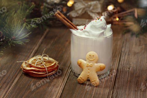 Preview: gingerbread man glass glass with eggnog on wooden brown table spruce branches dried orange slices