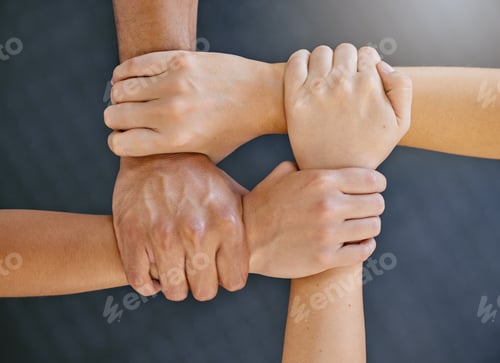 Preview: Closeup of diverse group of people from above holding each others wrists in a circle to express uni