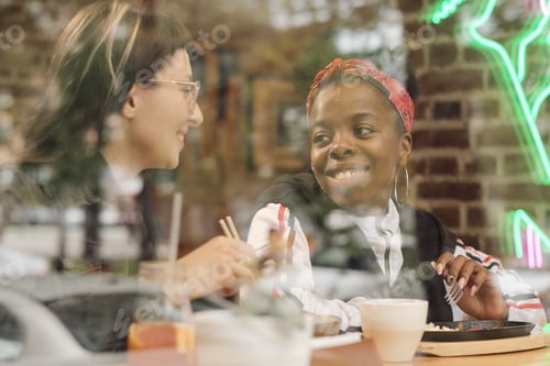 Preview: Happy young intercultural girlfriends looking at one another
