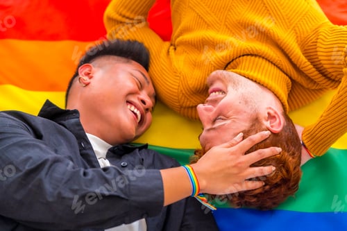 Preview: Beautiful gay couple being romantic at home over rainbow flag, lgbt concept