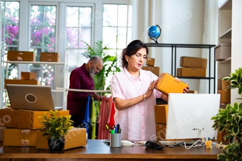 Preview: Indian senior couple doing E-commerce business from home, managing orders and packing boxes