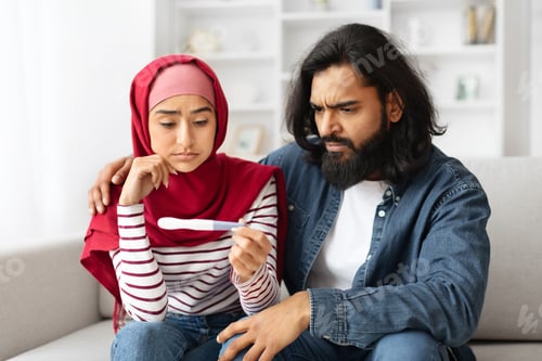 Preview: Infertility Problems. Upset Young Muslim Couple Looking At Negative Pregnancy Test