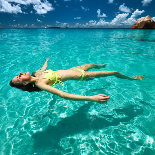 Preview: Woman In Yellow Bikini Lying On Water At Tropical Beach