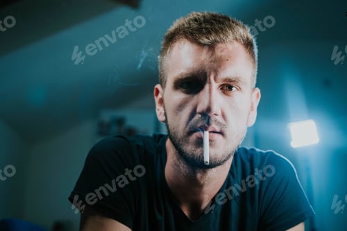 Preview: Bosnian Caucasian man smoking a cigarette while looking at the camera a serious face