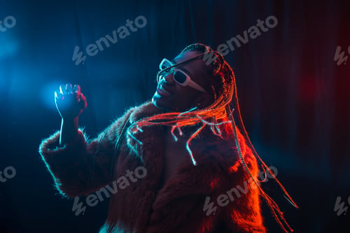 Preview: Black ethnic woman with braids with blue and red led lights, model having fun and dancing at party