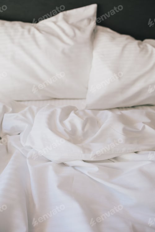 Vorschau: Bett und weiße Bettwäsche in einem Hotelzimmer.