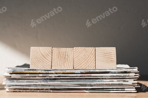 Preview: empty wooden blocks with copy space on pile of print newspapers