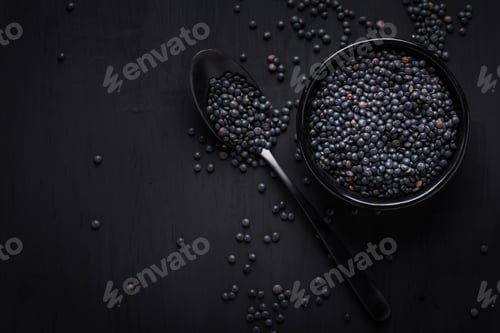 Preview: Beluga lentils on black background. Black lentils in bowl with spoon.