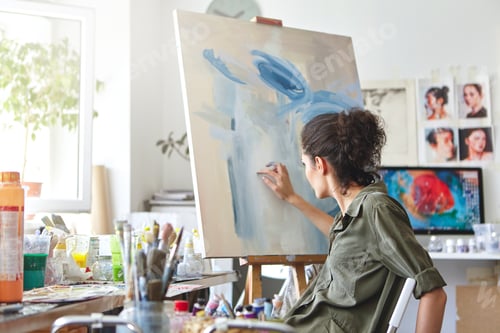 Preview: Art, creativity, hobby, job and creative occupation concept. Rear view of busy female artist sitting