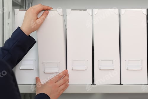 Preview: Woman taking folder with documents from shelf in archive, closeup