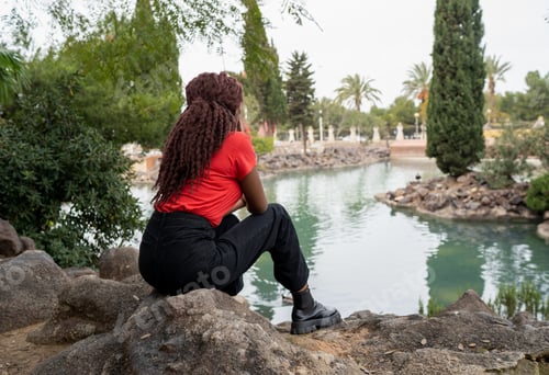 Preview: Unrecognizable black woman near pond
